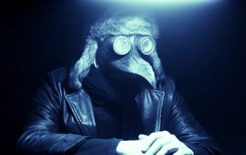 Filmbild aus 2551.03 - THE END, das einen Menschen mit einer Vogelmaske und einer Lederjacke zeigt.