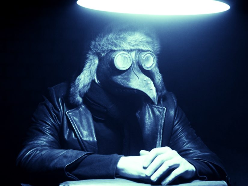 Filmbild aus 2551.03 - THE END, das einen Menschen mit einer Vogelmaske und einer Lederjacke zeigt.