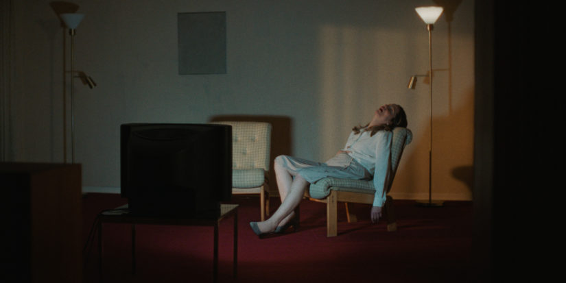 Filmstill zu ABOUT A HERO. Eine scheinbar leblose oder schlafende Frau in einem Wohnzimmersessel.