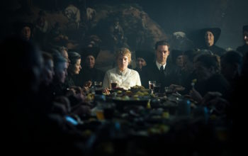 Filmbild aus WELCOME HOME BABY, das ein düsteres Bild einer Runde Menschen um eine gedeckte Tafel zeigt.